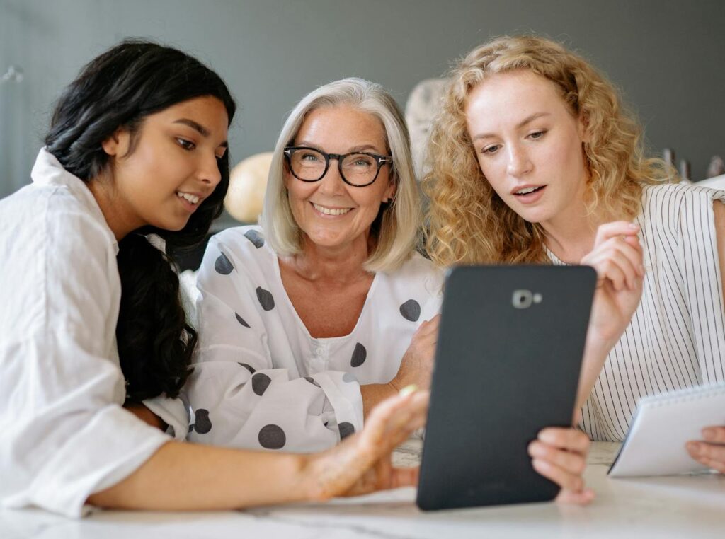 the ladies of diverse ages and backgrounds working together over a tablet